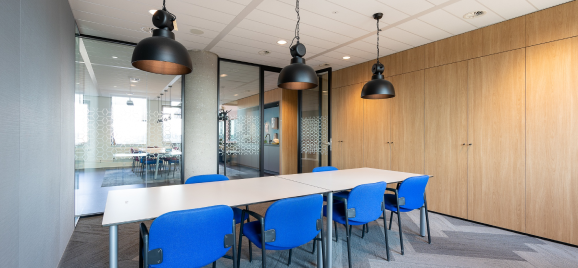 Shared office meeting room with blue chairs and timber wall panels