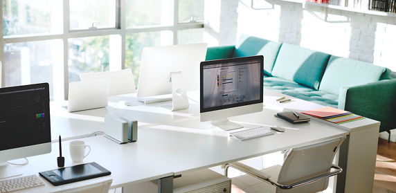 Hybrid workspace with desks, monitors and a green lounge sofa
