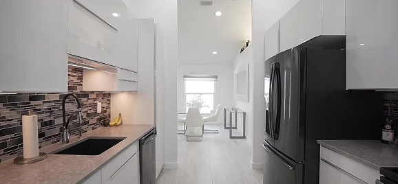 Fitted kitchen with mosaic backsplash and built-in appliances