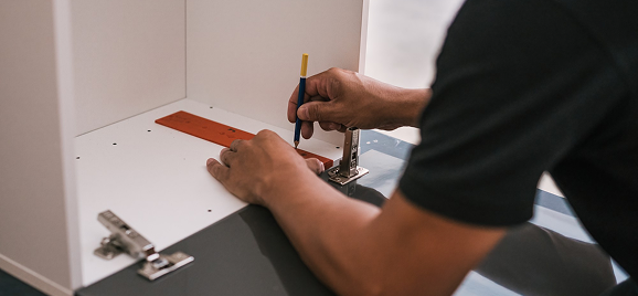 Carpenter marking a cabinet panel before installation