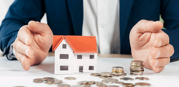 Model house surrounded by coins, representing property investment